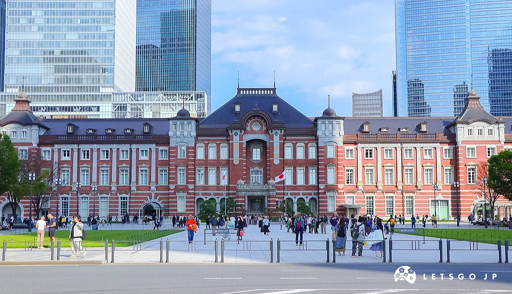 東京車站丸之內站房正面外觀,紅磚牆面搭配灰色圓頂,前方廣場有許多遊客。